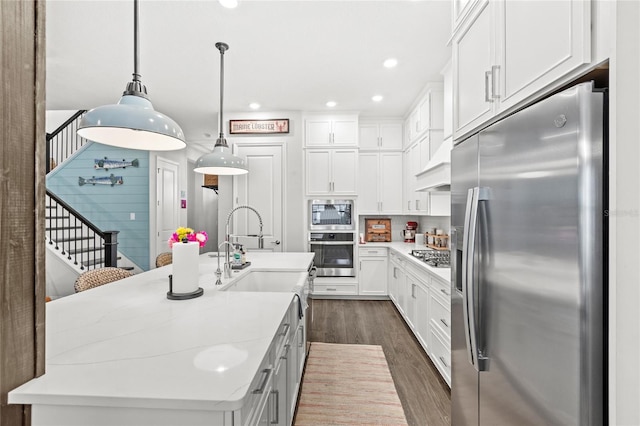 kitchen with a center island with sink, white cabinets, dark wood-type flooring, stainless steel appliances, and light countertops