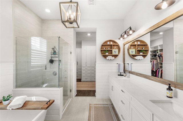 bathroom featuring a stall shower, a sink, a spacious closet, and double vanity