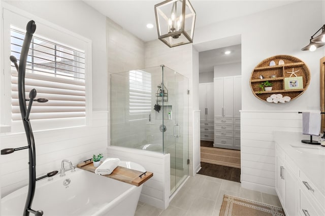 bathroom featuring a wainscoted wall, recessed lighting, a soaking tub, a stall shower, and vanity