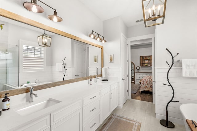 bathroom featuring double vanity, a freestanding bath, a shower with shower door, connected bathroom, and a sink