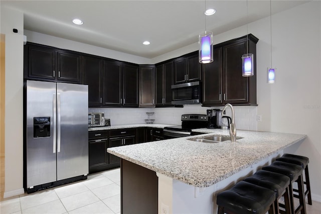 kitchen featuring light stone counters, stainless steel appliances, a peninsula, a sink, and decorative backsplash