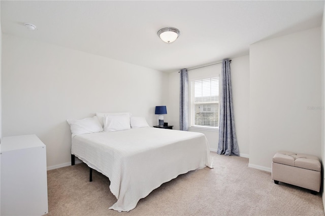 bedroom with light colored carpet and baseboards