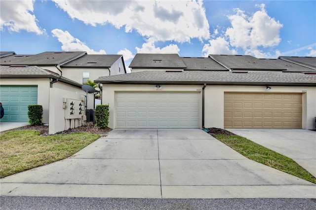 townhome / multi-family property with a garage, roof with shingles, concrete driveway, and stucco siding