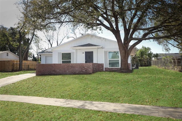 view of front of property with a front yard, fence, and brick siding