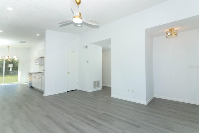 unfurnished living room featuring recessed lighting, ceiling fan with notable chandelier, wood finished floors, visible vents, and baseboards