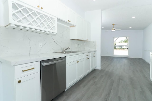 kitchen featuring light wood finished floors, decorative backsplash, stainless steel dishwasher, white cabinets, and a sink