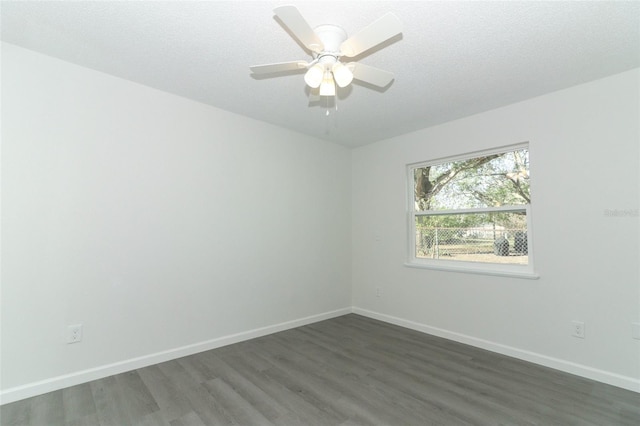 empty room with dark wood-type flooring, a textured ceiling, and baseboards