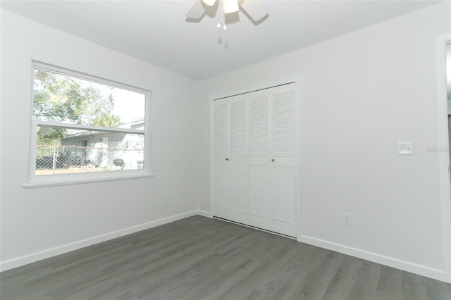 unfurnished bedroom with a textured ceiling, a closet, baseboards, and wood finished floors