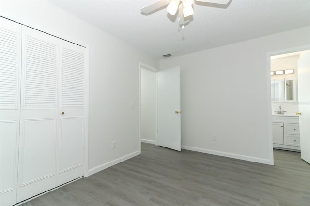 unfurnished bedroom with baseboards, visible vents, connected bathroom, wood finished floors, and a sink