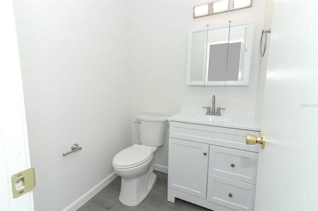 half bathroom featuring toilet, vanity, and baseboards