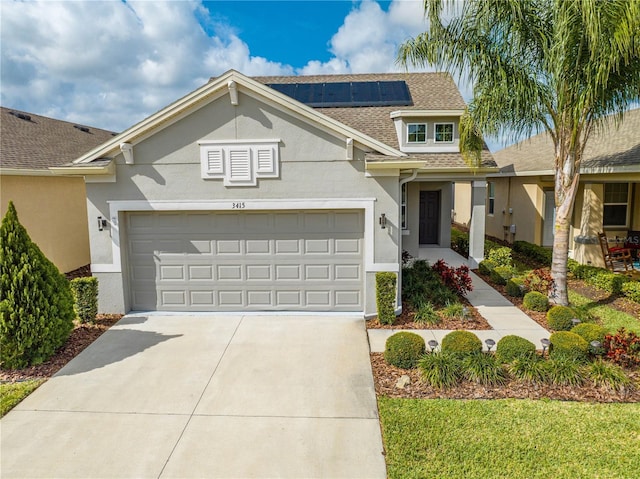 view of front of home featuring driveway, roof with shingles, an attached garage, roof mounted solar panels, and stucco siding