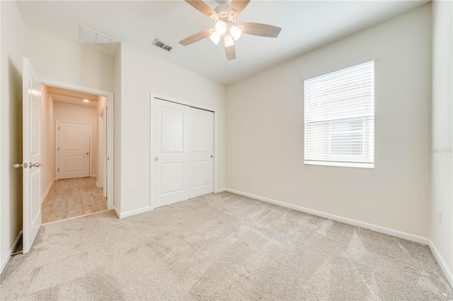 unfurnished bedroom with carpet flooring, a ceiling fan, visible vents, baseboards, and a closet