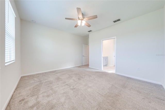 unfurnished bedroom featuring baseboards, visible vents, ensuite bathroom, and light colored carpet