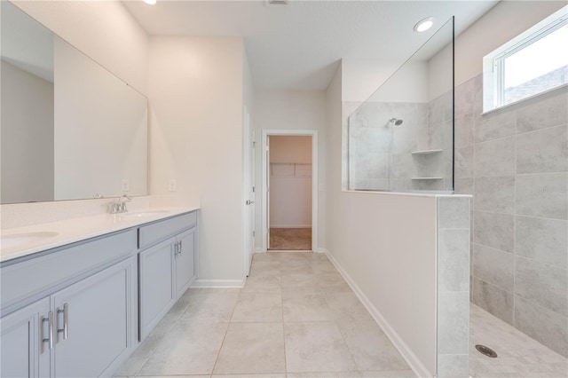 full bath featuring a sink, baseboards, a walk in closet, double vanity, and walk in shower