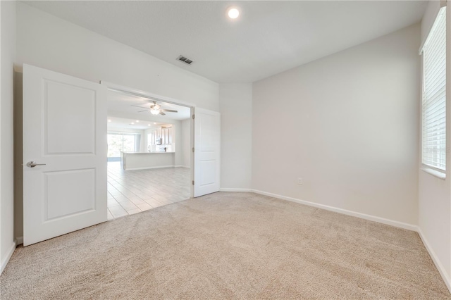 carpeted empty room with baseboards, visible vents, ceiling fan, and a wealth of natural light