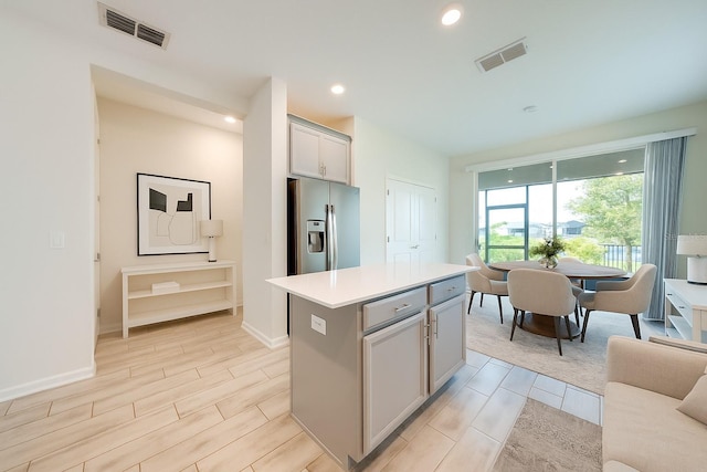3415 Sagebrush St, Harmony, FL 34773 - kitchen with stainless steel fridge with ice dispenser, a center island, light countertops, wood finish floors, and gray cabinetry