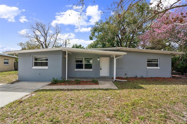 view of front of property with concrete block siding and a front lawn