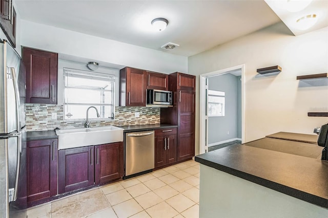 kitchen with visible vents, a sink, stainless steel appliances, dark countertops, and tasteful backsplash