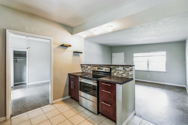 kitchen featuring dark countertops, tasteful backsplash, baseboards, light colored carpet, and electric stove