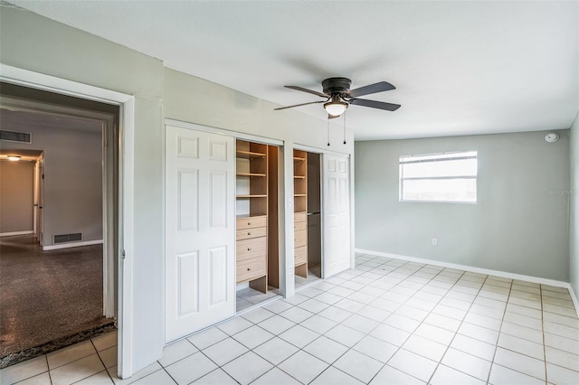 unfurnished bedroom featuring light tile patterned flooring, visible vents, two closets, and baseboards