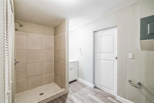 bathroom with baseboards, vanity, wood finished floors, and a shower stall