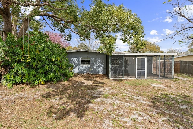 back of property featuring a sunroom and fence