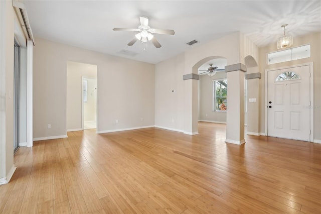 entryway featuring visible vents, arched walkways, ceiling fan with notable chandelier, and light wood finished floors