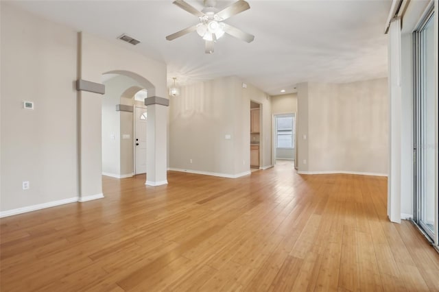 interior space with visible vents, baseboards, ceiling fan, light wood-style flooring, and arched walkways