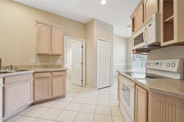 kitchen with a sink, white appliances, light tile patterned flooring, and light brown cabinetry