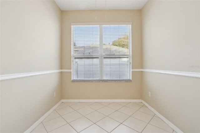 empty room featuring baseboards and light tile patterned flooring