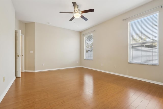 spare room featuring baseboards, wood finished floors, and a ceiling fan