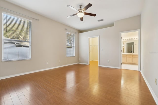 unfurnished bedroom featuring visible vents, baseboards, hardwood / wood-style floors, and a spacious closet