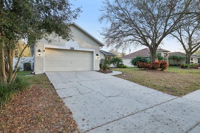 exterior space with a garage, a front yard, driveway, and stucco siding