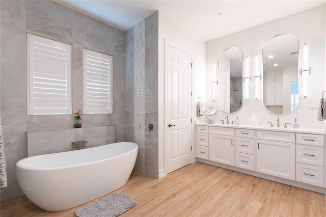 2161 Snow Rd, Orlando, FL 32814 - full bathroom featuring a sink, tile walls, wood finished floors, a freestanding bath, and double vanity