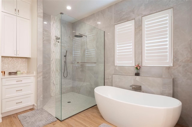 2161 Snow Rd, Orlando, FL 32814 - bathroom with a marble finish shower, wood finished floors, a soaking tub, tile walls, and recessed lighting