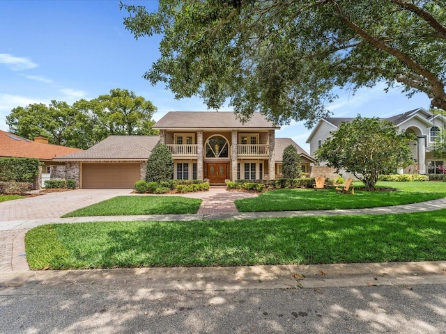 view of front of property featuring a garage, driveway, a front yard, and a balcony