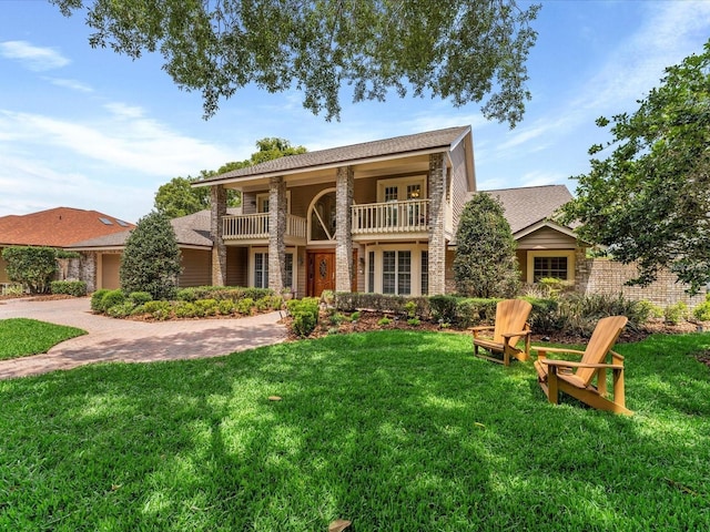 view of front of property with a shingled roof, a front yard, decorative driveway, and a balcony