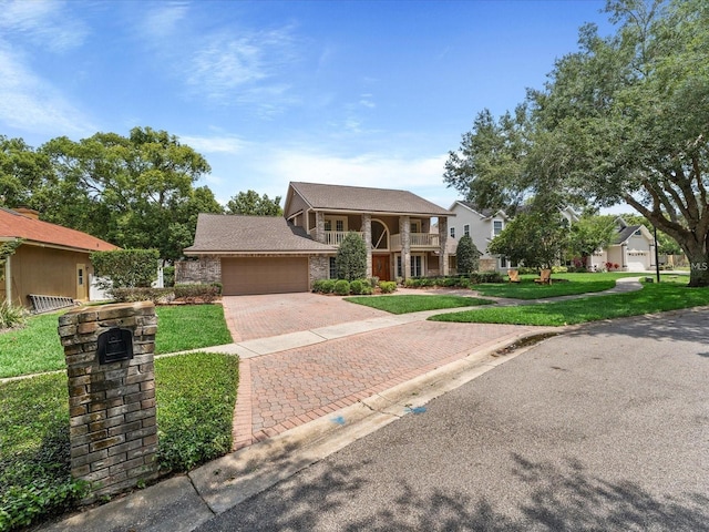 view of front of property featuring a garage, a front yard, decorative driveway, and a balcony