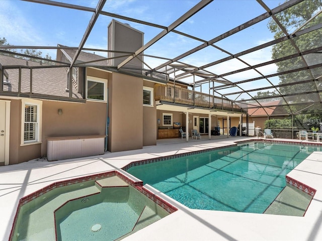 view of swimming pool featuring glass enclosure, a pool with connected hot tub, and a patio