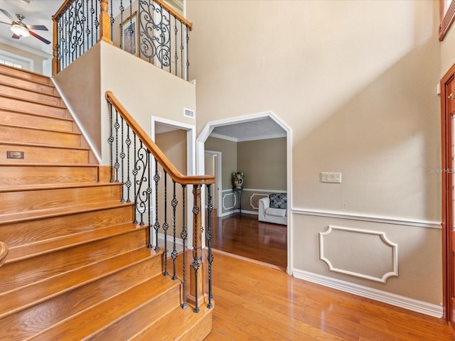 stairway featuring ornamental molding, wood finished floors, visible vents, and a ceiling fan