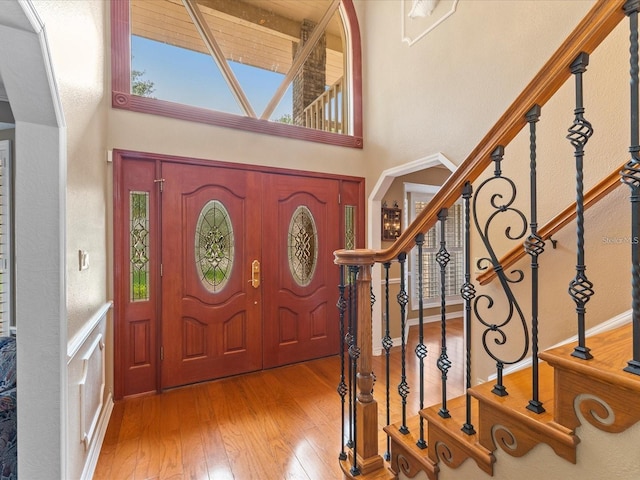 entryway with arched walkways, a high ceiling, hardwood / wood-style floors, and stairs