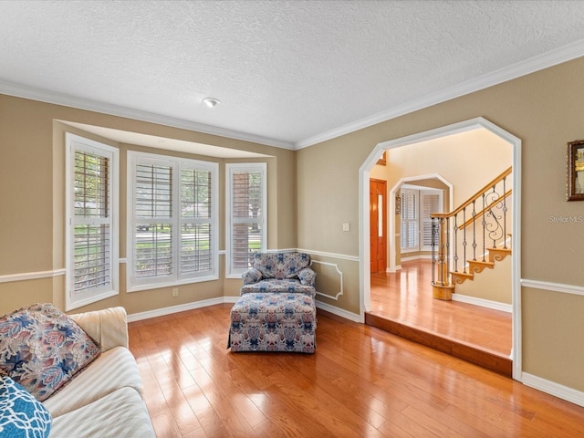 living room featuring wood-type flooring, a textured ceiling, arched walkways, and crown molding