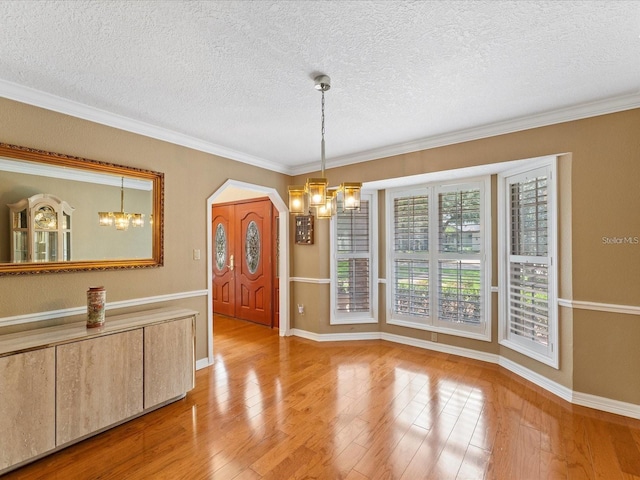 dining space with an inviting chandelier, crown molding, a textured ceiling, and wood finished floors