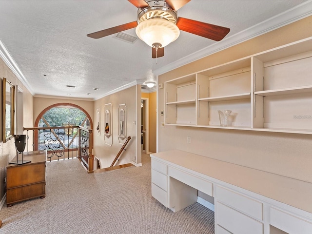 home office with visible vents, light colored carpet, ornamental molding, built in study area, and a textured ceiling