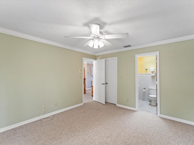 unfurnished bedroom featuring a textured ceiling, ensuite bathroom, light carpet, visible vents, and crown molding