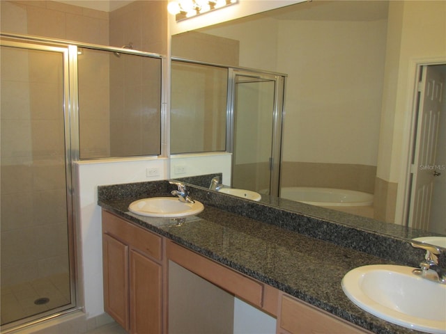 full bath featuring double vanity, a stall shower, and a sink