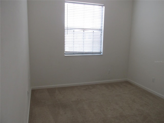 empty room featuring carpet floors and baseboards