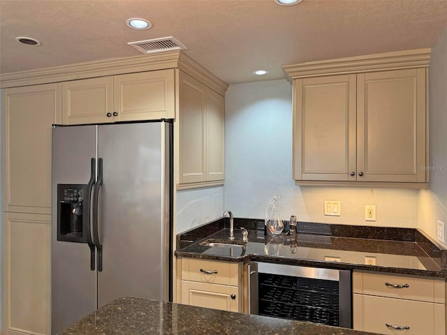 kitchen with beverage cooler, visible vents, dark stone counters, stainless steel refrigerator with ice dispenser, and a sink