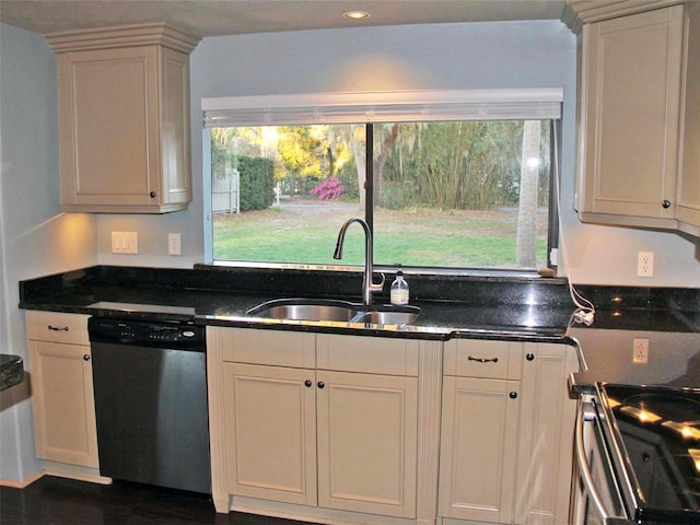 kitchen with appliances with stainless steel finishes, dark stone counters, and a sink