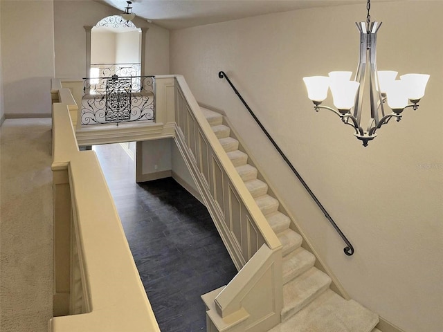 staircase with an inviting chandelier, baseboards, and wood finished floors